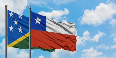 Solomon Islands and Chile flag waving in the wind against white cloudy blue sky together. Diplomacy...