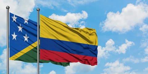 Solomon Islands and Colombia flag waving in the wind against white cloudy blue sky together. Diplomacy concept, international relations.