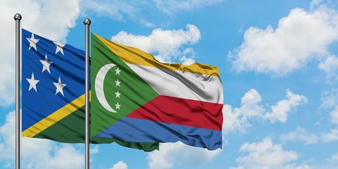 Solomon Islands and Comoros flag waving in the wind against white cloudy blue sky together. Diplomacy concept, international relations.