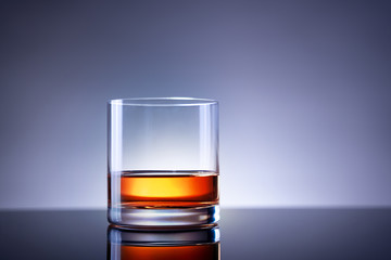 Elegant simple glass of luxury whisky against bluish background