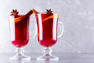 Two glasses of mulled wine with spices on cement background. Christmas mulled wine with orange, star anise and cinnamon. Red mulled wine on a gray background. Minimalism. Copy space