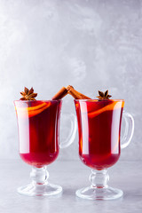 Two glasses of mulled wine with spices on cement background. Christmas mulled wine with orange, star anise and cinnamon. Red mulled wine on a gray background. Minimalism. Copy space