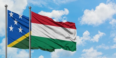 Solomon Islands and Hungary flag waving in the wind against white cloudy blue sky together. Diplomacy concept, international relations.