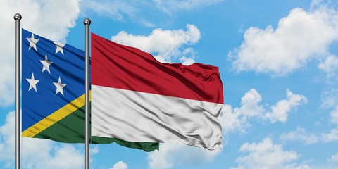 Solomon Islands and Indonesia flag waving in the wind against white cloudy blue sky together. Diplomacy concept, international relations.