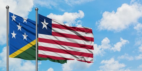 Solomon Islands and Liberia flag waving in the wind against white cloudy blue sky together. Diplomacy concept, international relations.