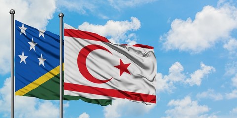 Solomon Islands and Northern Cyprus flag waving in the wind against white cloudy blue sky together....