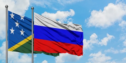 Solomon Islands and Russia flag waving in the wind against white cloudy blue sky together. Diplomacy concept, international relations.