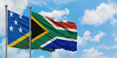 Solomon Islands and South Africa flag waving in the wind against white cloudy blue sky together. Diplomacy concept, international relations.