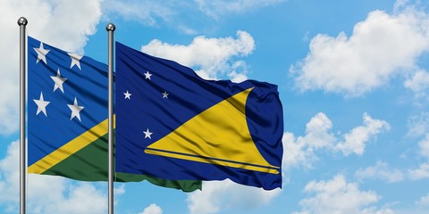 Solomon Islands and Tokelau flag waving in the wind against white cloudy blue sky together. Diplomacy concept, international relations.