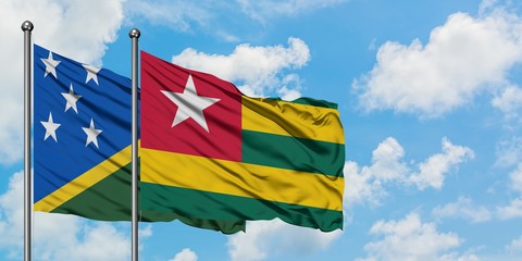 Solomon Islands and Togo flag waving in the wind against white cloudy blue sky together. Diplomacy concept, international relations.