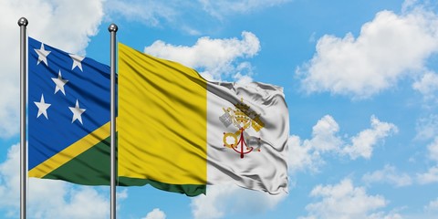 Solomon Islands and Vatican City flag waving in the wind against white cloudy blue sky together. Diplomacy concept, international relations.