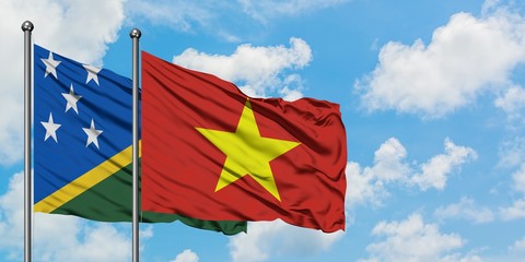Solomon Islands and Vietnam flag waving in the wind against white cloudy blue sky together. Diplomacy concept, international relations.