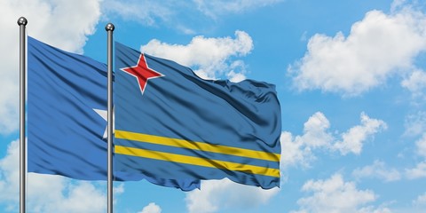 Somalia and Aruba flag waving in the wind against white cloudy blue sky together. Diplomacy concept, international relations.