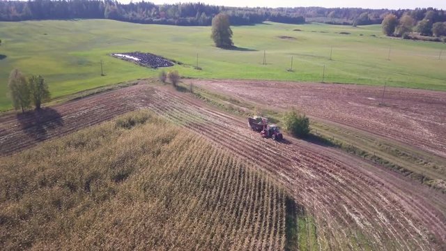 Aerial shot of a tractor driving into a corn field, ready for harvesting.