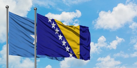 Somalia and Bosnia Herzegovina flag waving in the wind against white cloudy blue sky together....