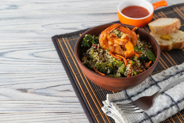 Cooked quinoa with fresh vegetables and fried shrimps in a bowl