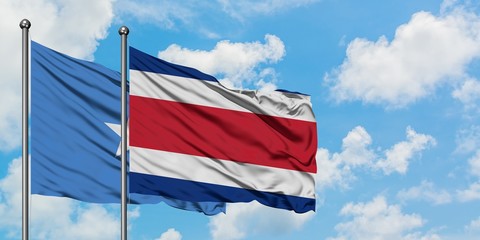 Somalia and Costa Rica flag waving in the wind against white cloudy blue sky together. Diplomacy concept, international relations.