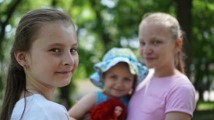 Portrait of three smiling girls posing in a park in the summer