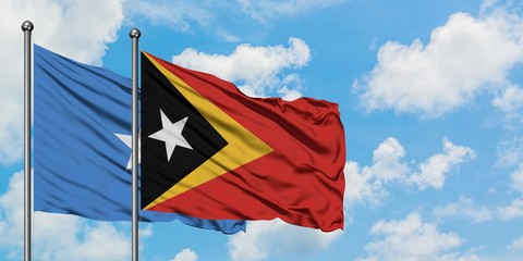 Somalia and East Timor flag waving in the wind against white cloudy blue sky together. Diplomacy concept, international relations.