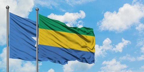 Somalia and Gabon flag waving in the wind against white cloudy blue sky together. Diplomacy...