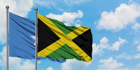 Somalia and Jamaica flag waving in the wind against white cloudy blue sky together. Diplomacy concept, international relations.