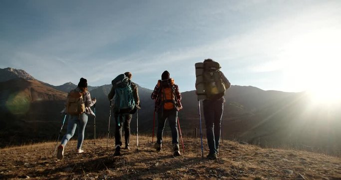 Group of four young people having a hiking tour, going for trekking adventure together, reaching top of mountain and cheering - friendship, achievement concept 4k footage