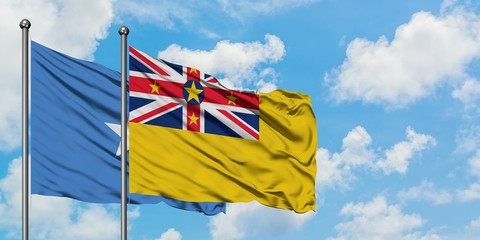 Somalia and Niue flag waving in the wind against white cloudy blue sky together. Diplomacy concept, international relations.