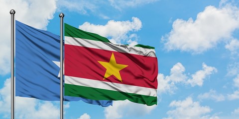 Somalia and Suriname flag waving in the wind against white cloudy blue sky together. Diplomacy concept, international relations.