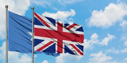 Somalia and United Kingdom flag waving in the wind against white cloudy blue sky together. Diplomacy concept, international relations.