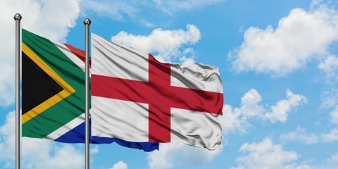 South Africa and England flag waving in the wind against white cloudy blue sky together. Diplomacy concept, international relations.