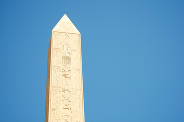 Bright blue sky view of finely detailed hieroglyphs line the well preserved obelisk at Karnak in...