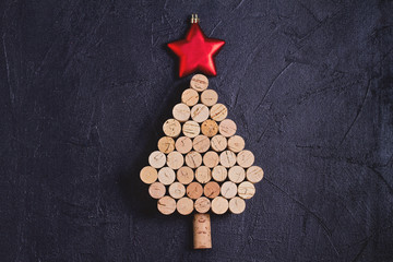 Fototapeta na wymiar Christmas tree made of wine corks on black background. Layout, flat lay, template. New Year winter holidays background