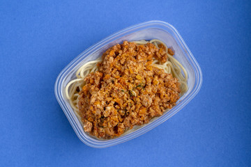 Pasta with minced meat and onion in navy-style on a blue background.