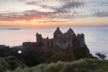 Obraz premium Dunluce Castle in Northern Ireland during a stunning sunset.