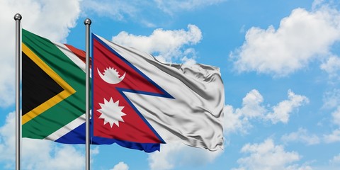 South Africa and Nepal flag waving in the wind against white cloudy blue sky together. Diplomacy concept, international relations.