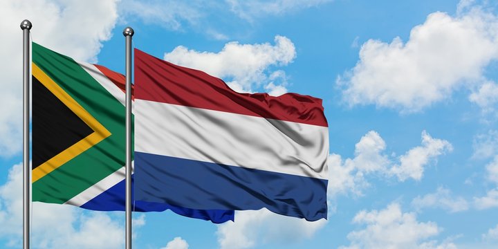 South Africa and Netherlands flag waving in the wind against white cloudy blue sky together. Diplomacy concept, international relations.