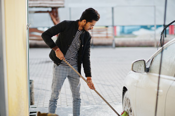 South asian man or indian male washing his white transportation on car wash.