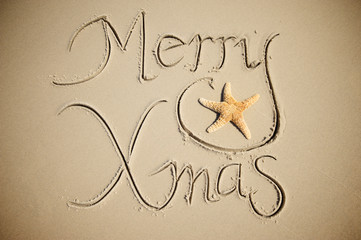 Tropical holiday Merry Xmas message on smooth sand beach featuring a cute starfish