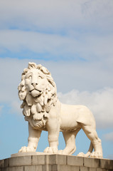 Fototapeta premium White stone statue of a lion, also known as the Westminster Bridge Lion (erected in 1837), standing against soft blue sky in London, UK