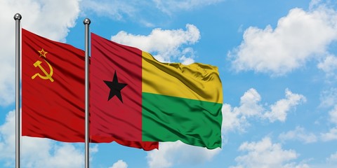 Soviet Union and Guinea Bissau flag waving in the wind against white cloudy blue sky together. Diplomacy concept, international relations.