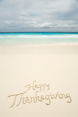 Tropical Happy Thanksgiving travel message handwritten in calligraphy on smooth sand beach