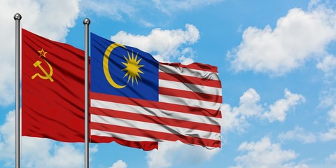 Soviet Union and Malaysia flag waving in the wind against white cloudy blue sky together. Diplomacy concept, international relations.