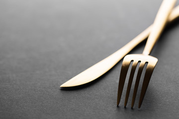 Gold cutlery set on black background - obrazy, fototapety, plakaty
