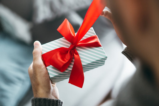 Man holding gift with red ribbon