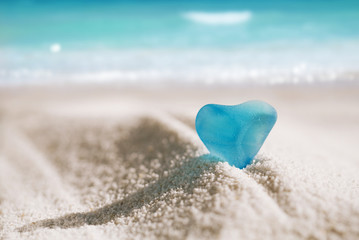 sea glass blue heart on white sand beach