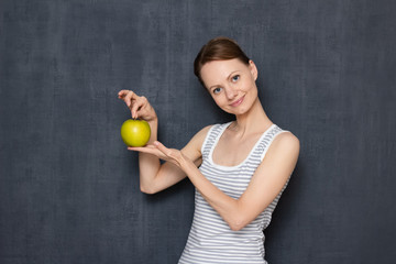 Portrait of happy young woman holding ripe apple in hands