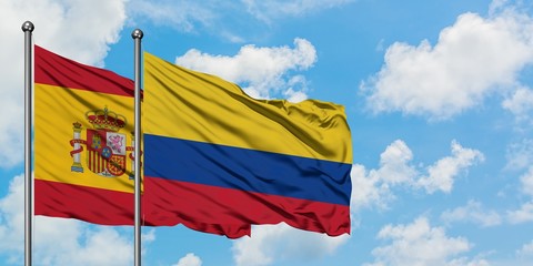 Spain and Colombia flag waving in the wind against white cloudy blue sky together. Diplomacy concept, international relations.