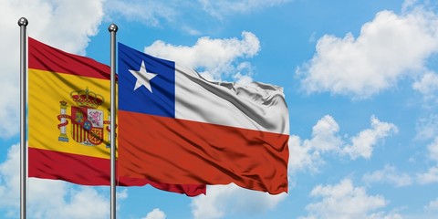 Spain and Chile flag waving in the wind against white cloudy blue sky together. Diplomacy concept, international relations.