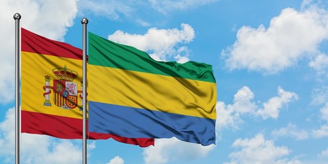 Spain and Gabon flag waving in the wind against white cloudy blue sky together. Diplomacy concept,...