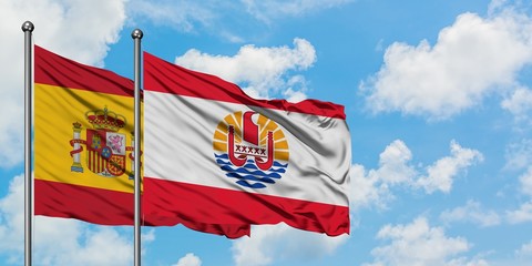 Spain and French Polynesia flag waving in the wind against white cloudy blue sky together. Diplomacy concept, international relations.